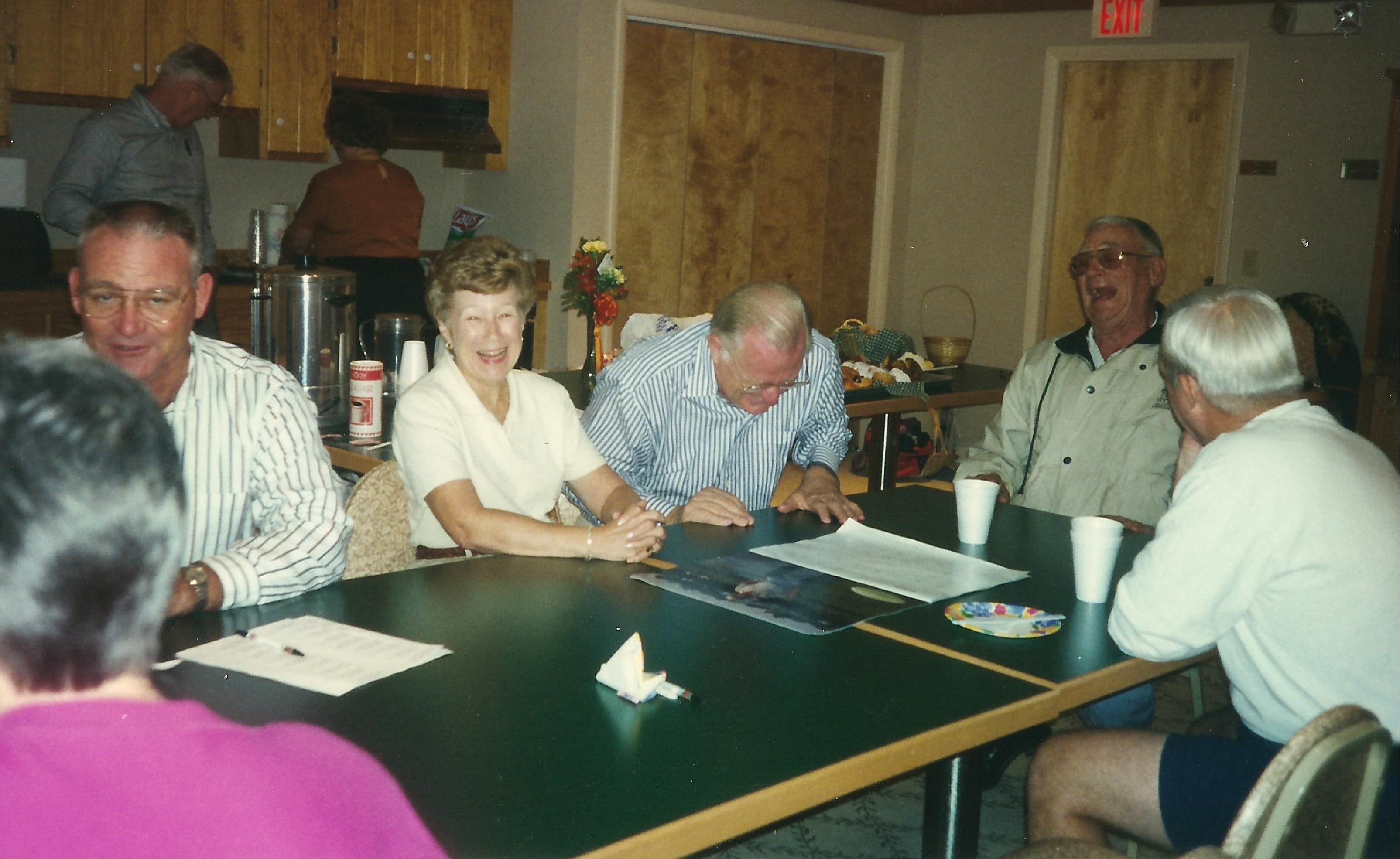 A meeting around the table in the Refuge Inn meeting room, papers and cups out.