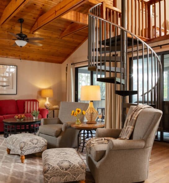 A cozy living room featuring a spiral staircase, comfortable seating, and warm wooden accents.