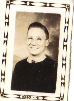 Black and white portrait of a smiling young person wearing glasses and a dark sweater.