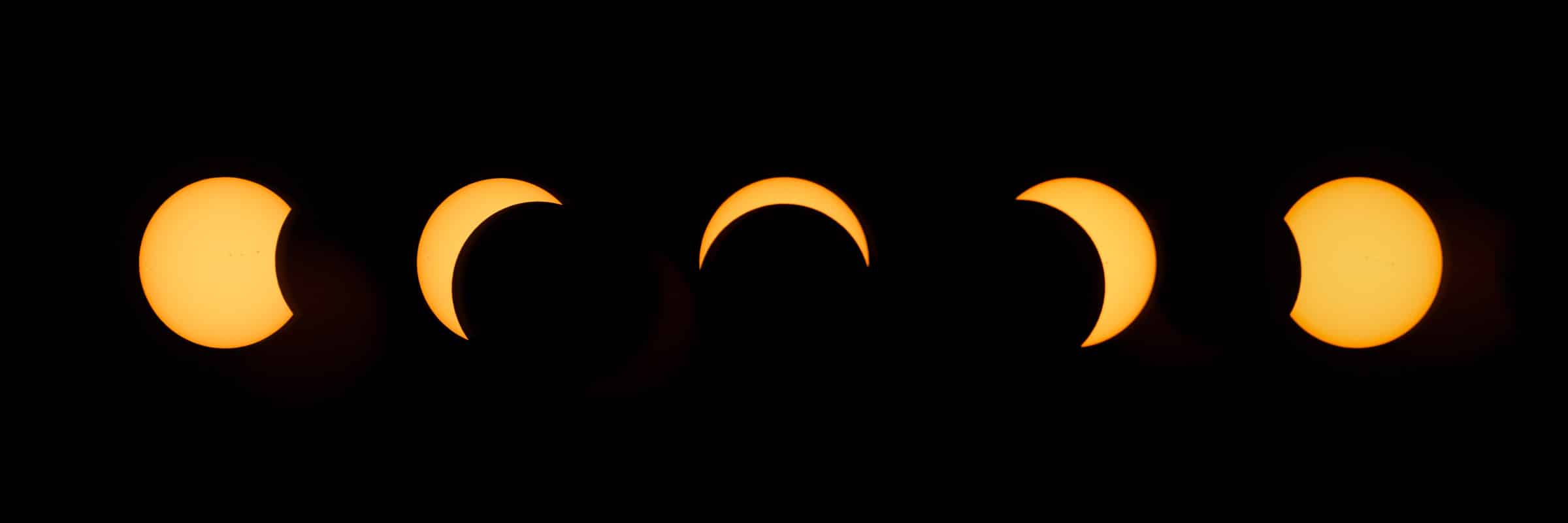 Five phases of a solar eclipse against a black background.