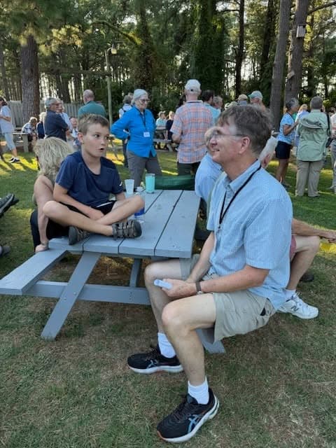Birders talking at a picnic table on the back lawn of the Refuge Inn during the Virginia Society of Ornithology's Friday Meet-and-Greet.
