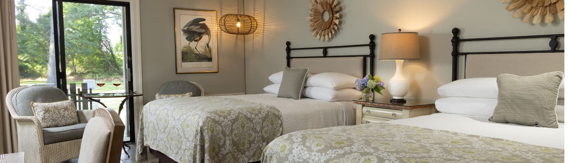 A cozy hotel room featuring two beds, a comfortable seating area, and large windows with outdoor views.