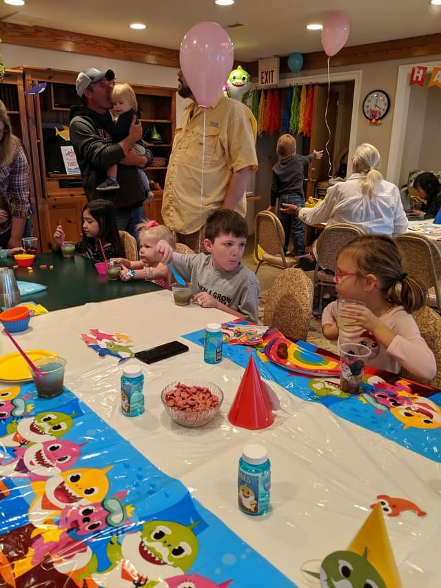 A child’s birthday party in the Refuge Inn meeting room, with balloons and a decorated table.