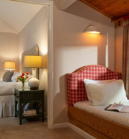 Cozy bedroom with a plaid daybed, a bedside table, and warm lighting.