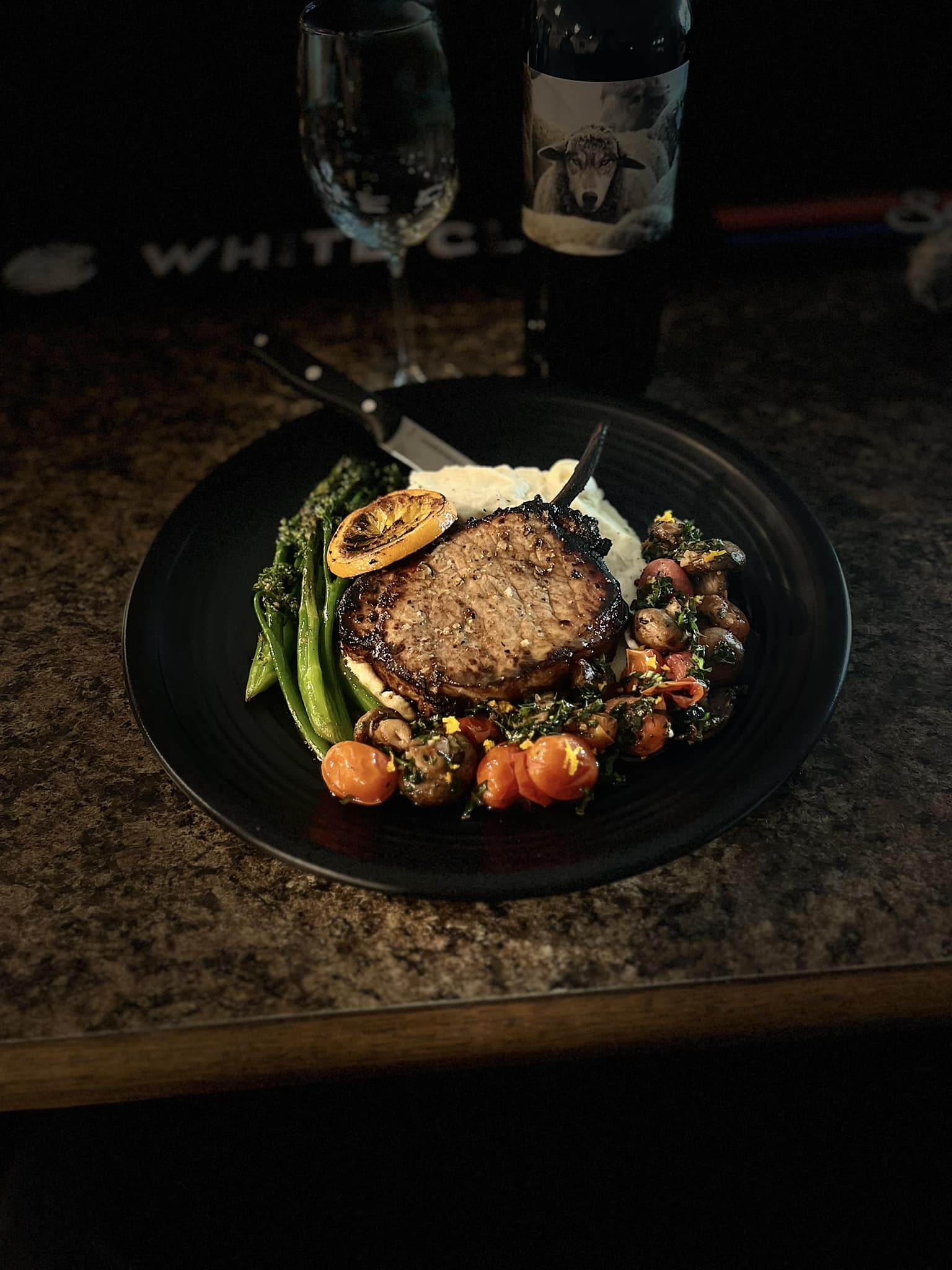 A gourmet meal featuring a grilled steak, sautéed vegetables, and mashed potatoes, accompanied by a glass of wine.