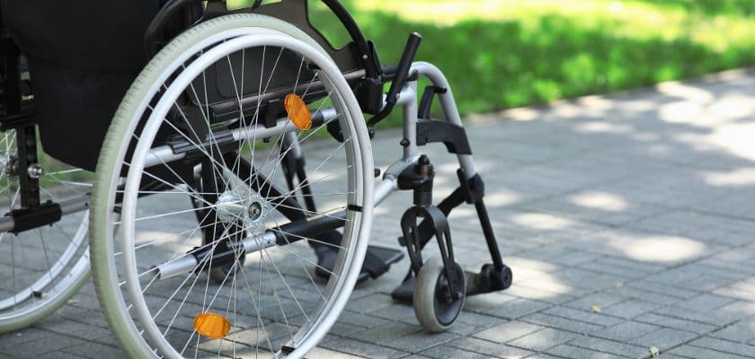 A wheelchair on a paved path with green grass in the background.
